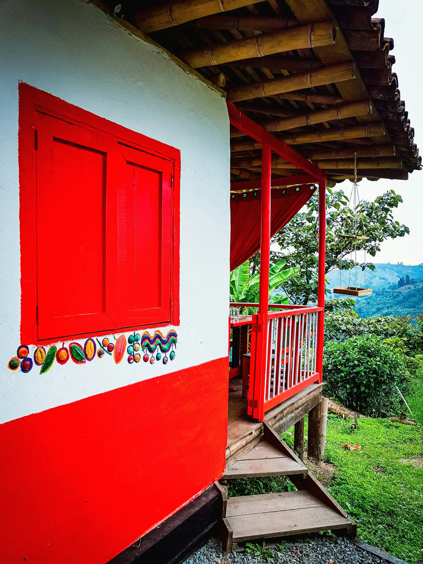 Casa cafetera blanca con puertas y ventanas rojas en una finca de Caldas, Colombia